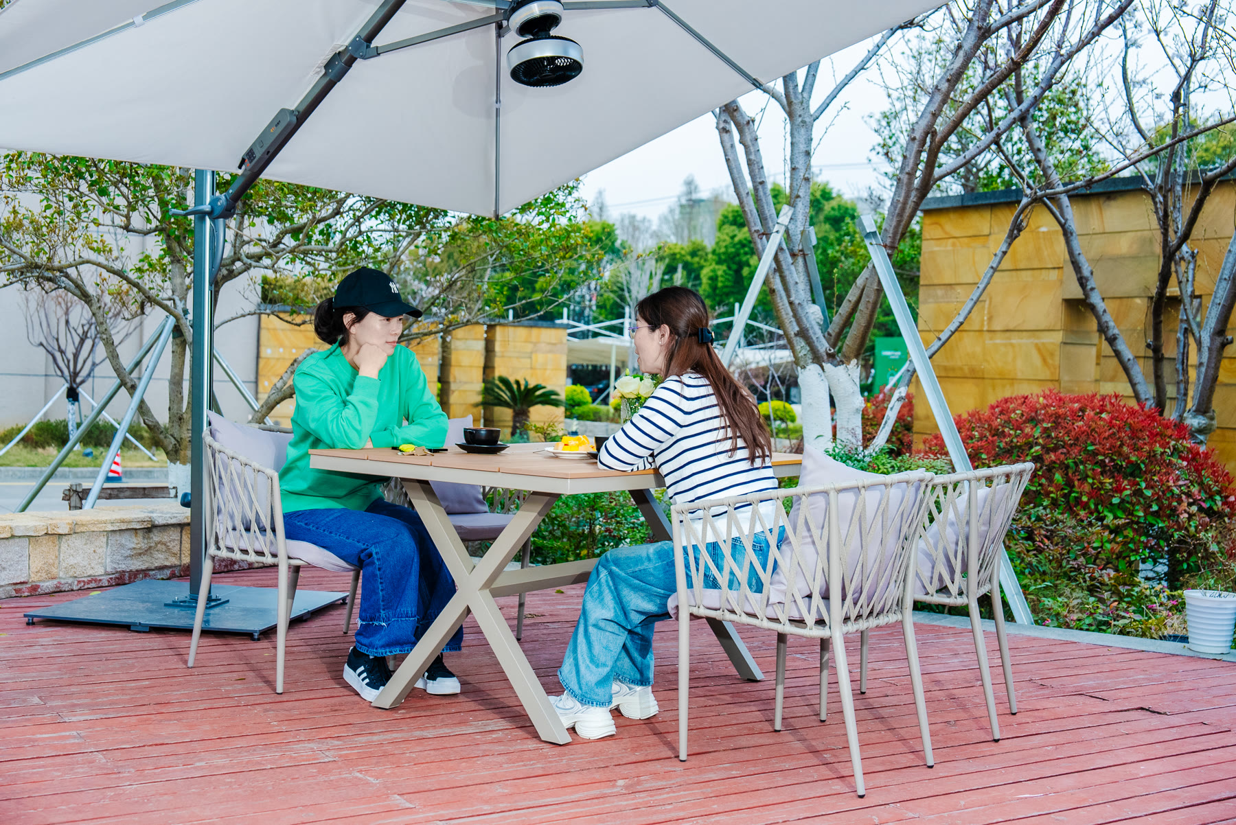 Des amis savourant des boissons et une conversation sous un parasol solaire dans un café en plein air