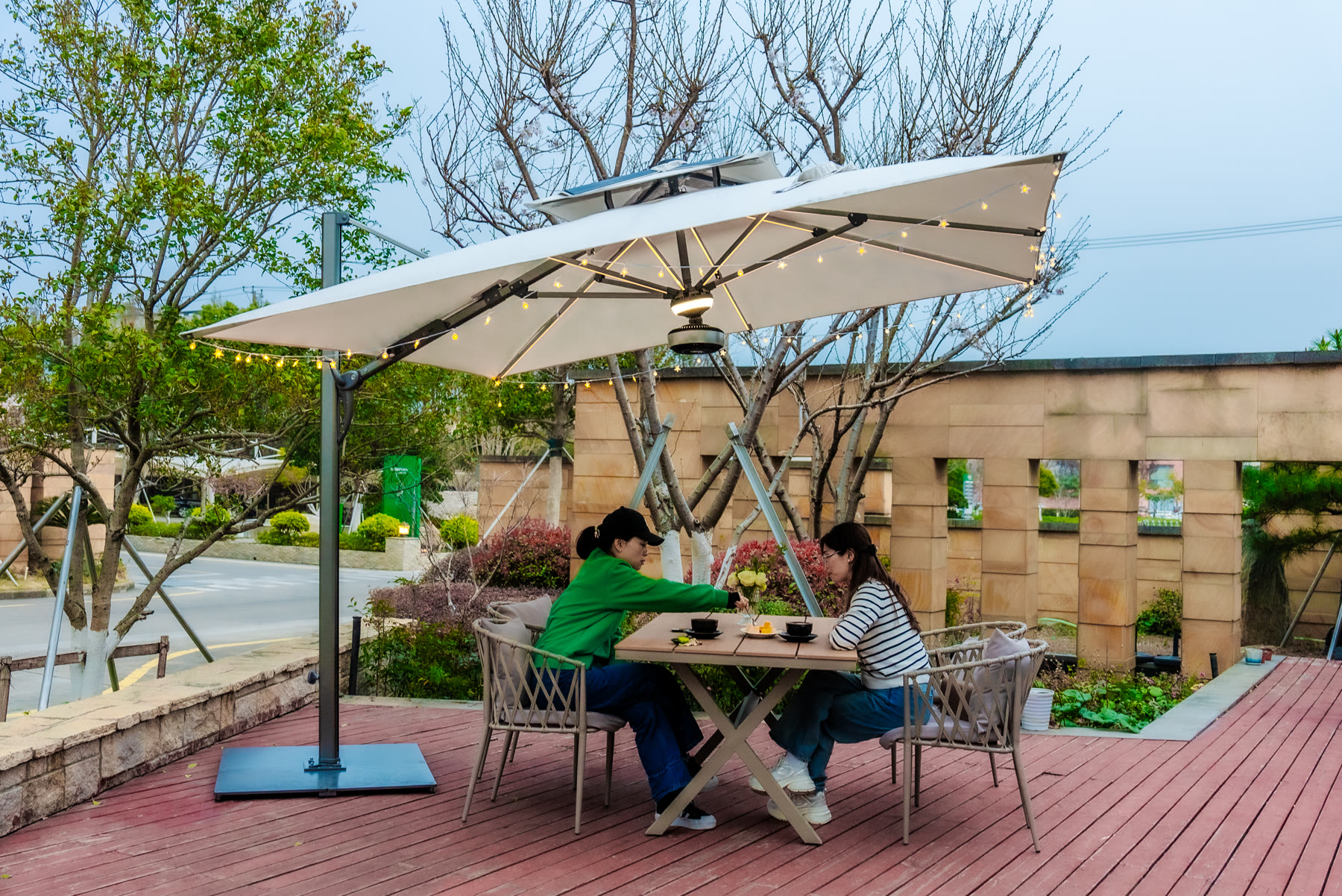 Des invités profitant d'un éclairage nocturne chaleureux sous un parasol solaire Solargy